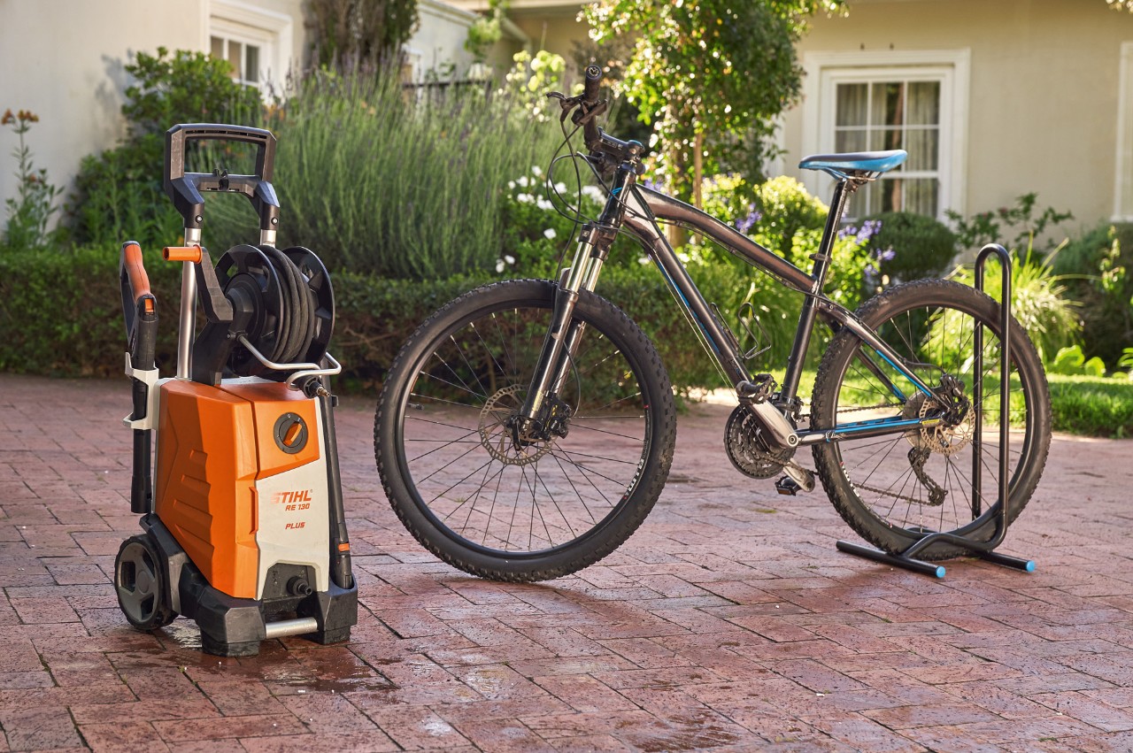 Una bicicleta recién lavada delante de una casa junto a una hidrolimpiadora STIHL RE 130 plus