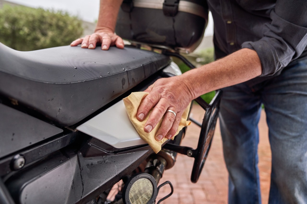 Cómo lavar tu moto en casa: primer plano de la aplicación de cera con un paño suave en una zona pintada de una moto. 