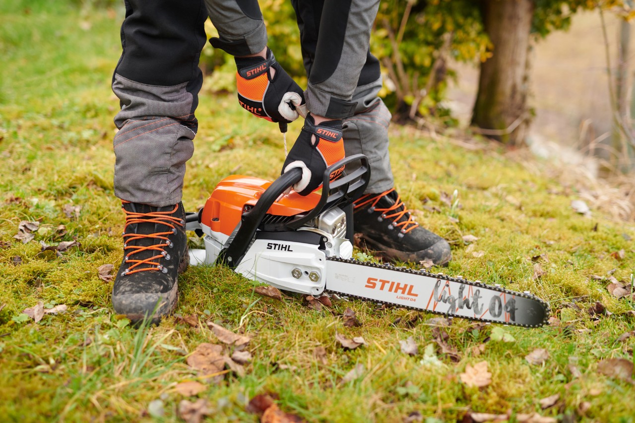 Una persona con guantes pone en marcha una motosierra de gasolina STIHL MS 261 C-M con espada Light 04
