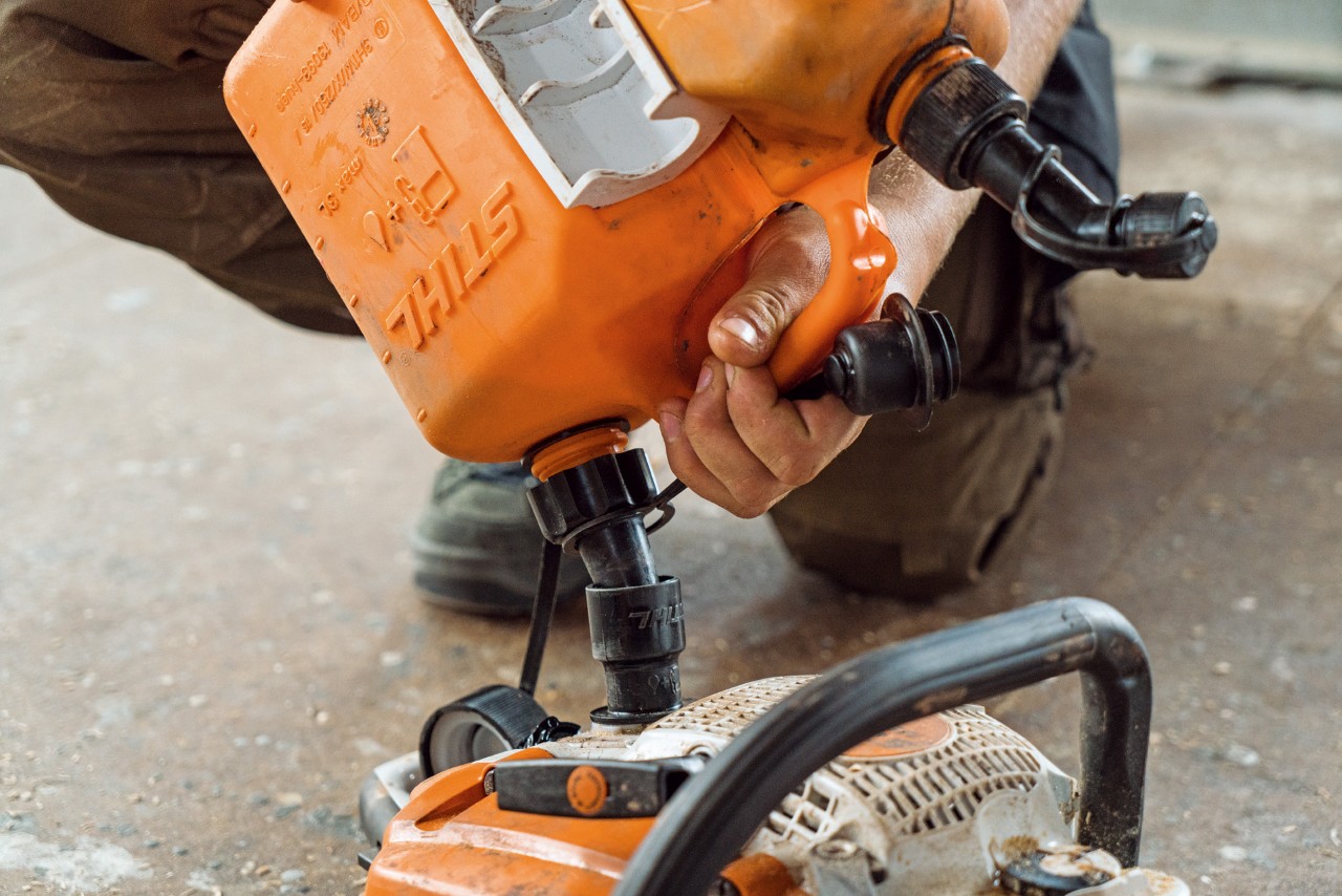 Primer plano del llenado de una motosierra STIHL desde un bidón de mezcla de gasolina para motosierra