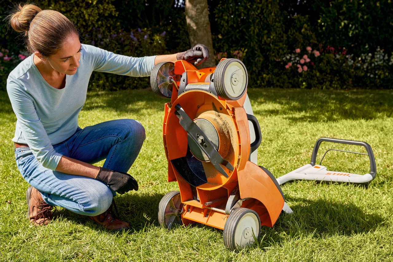 Una mujer mira bajo su cortacésped de batería STIHL RMA 339C en el jardín