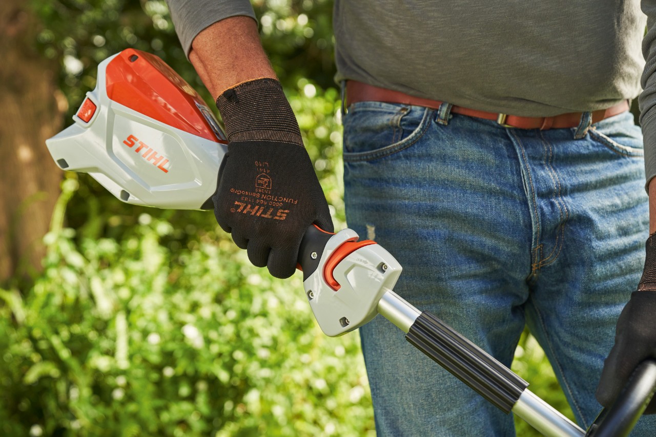 Un hombre con guantes de protección acciona la palanca de cambio de la desbrozadora de batería STIHL FSA 60 para arrancarla