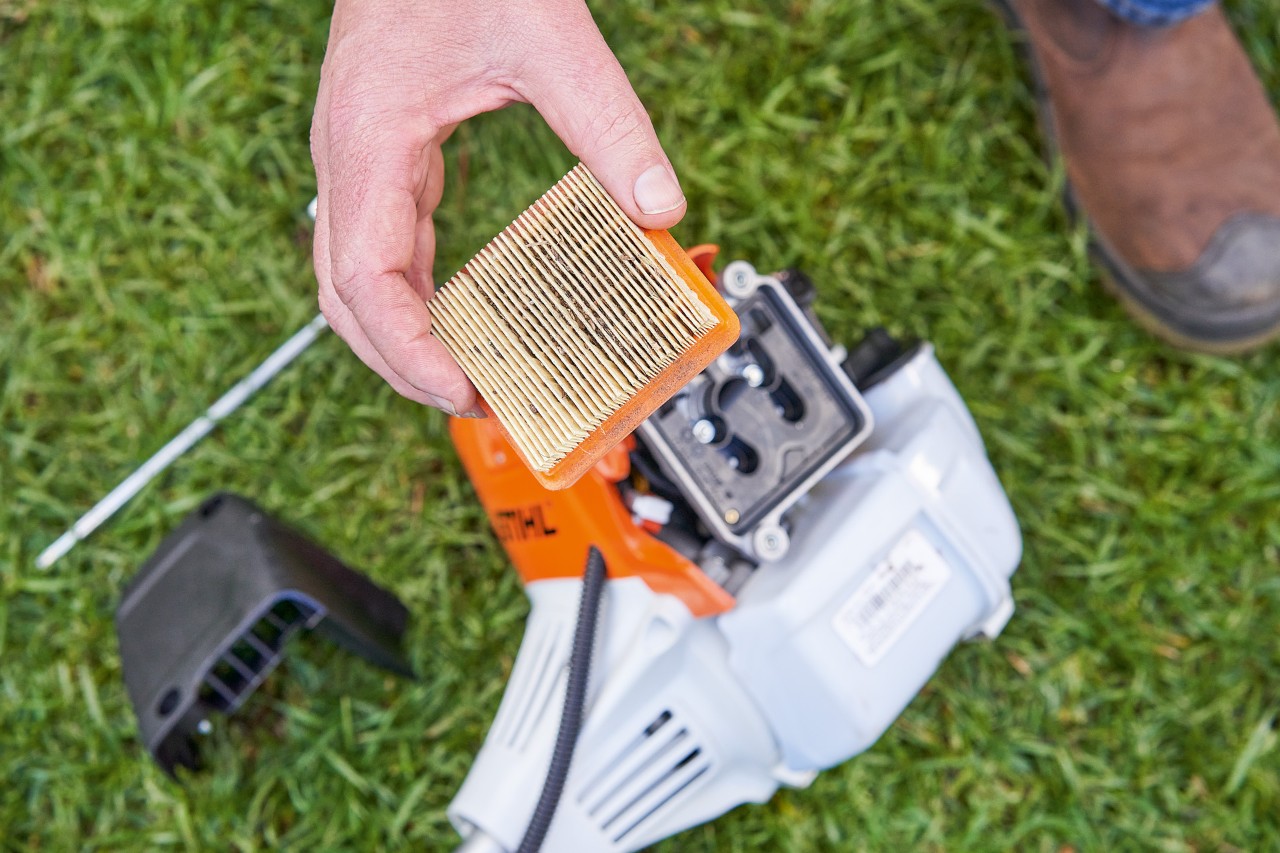 Una persona retira el filtro de aire de una desbrozadora STIHL para limpiarla 