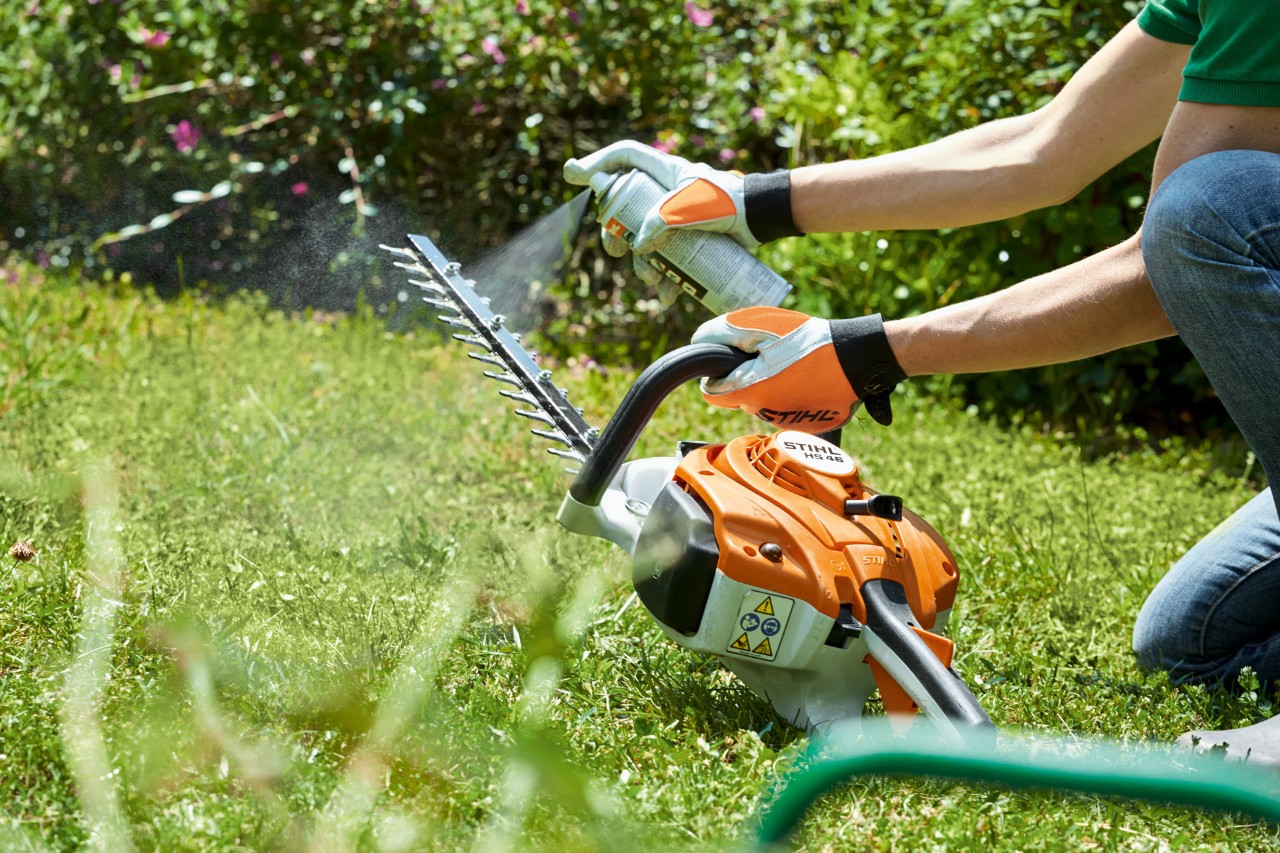  El cortasetos de gasolina STIHL HS 82 T se pulveriza sobre el césped verde para limpiarlo