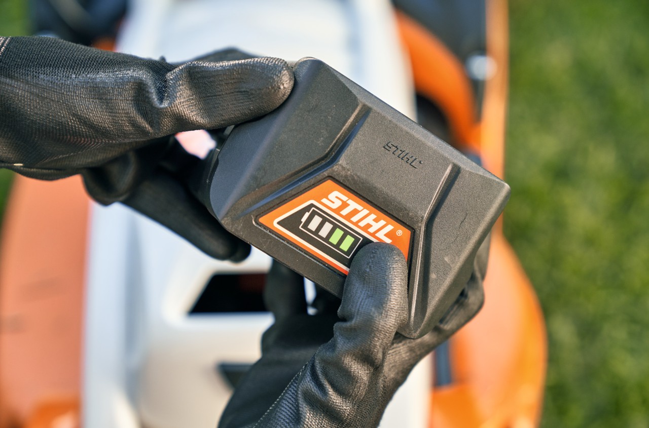Batería de litio-ion STIHL, en segundo plano un cortacésped de batería STIHL RMA 339 C