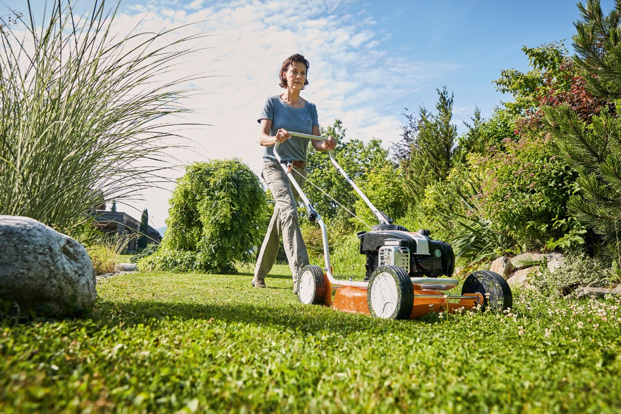 Mujer realizando mulching con un cortacésped de gasolina STIHL RM 2 R sobre un terreno verde