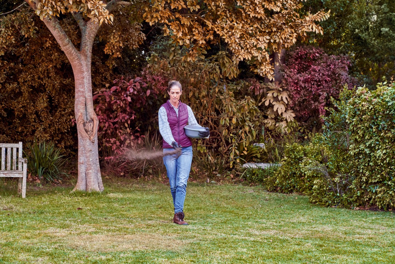 Mujer esparciendo fertilizantes en su jardín