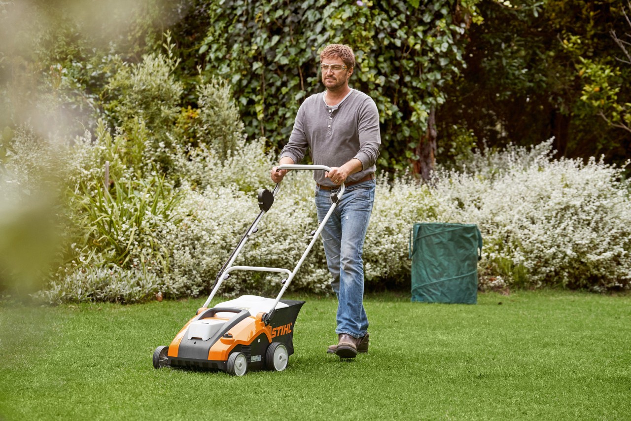 Un hombre escarifica un pasto verde con un escarificador STIHL RLA 240."