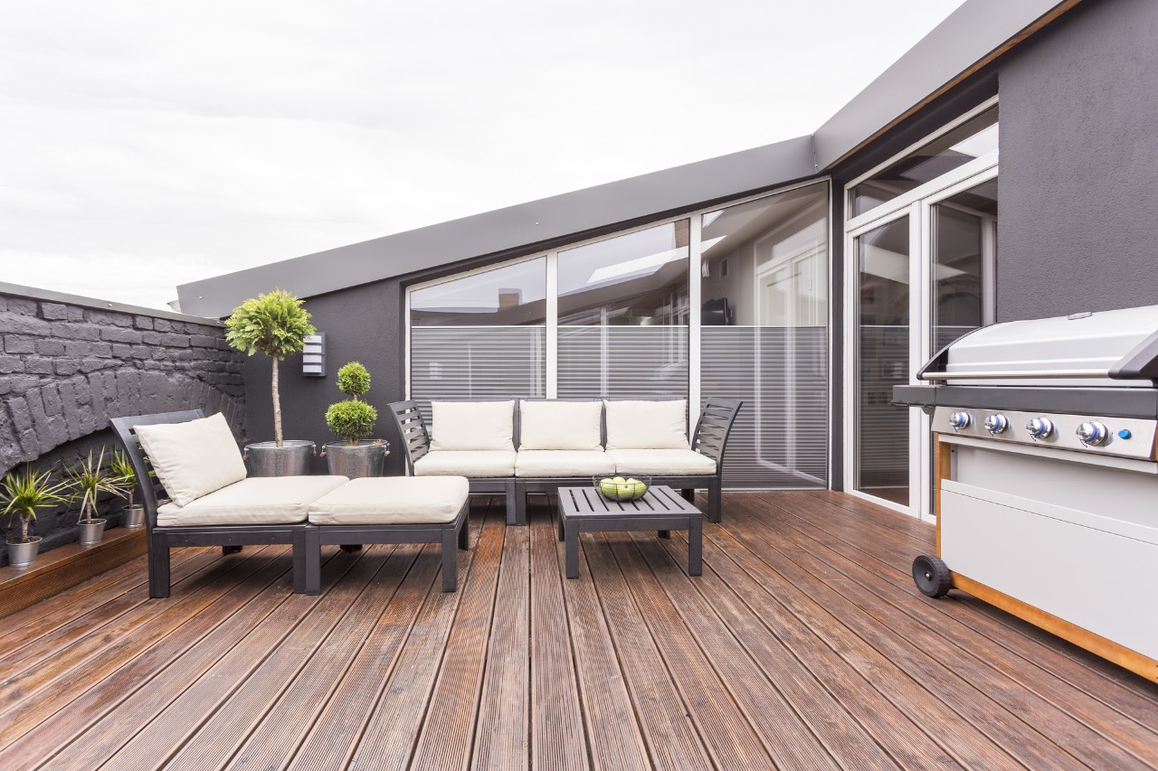Muebles de jardín, una barbacoa y plantas en una terraza con suelo de madera