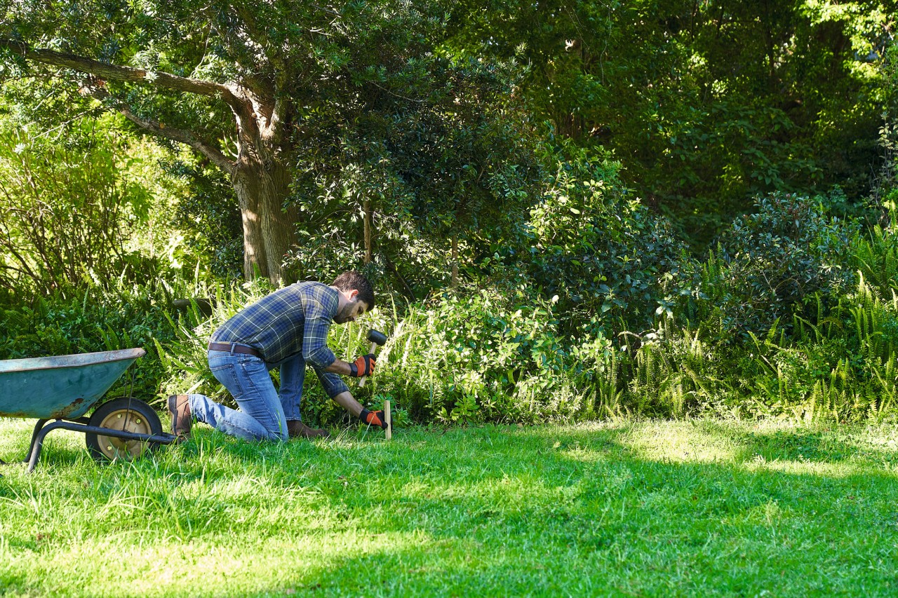 Un hombre marca la superficie para sembrar un campo de flores silvestres con cuerdas y estacas