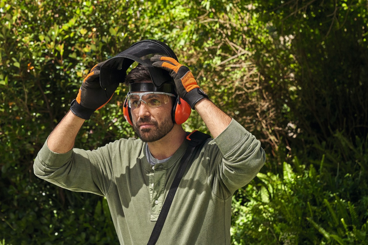 Un hombre con equipamiento de protección STIHL en un jardín 