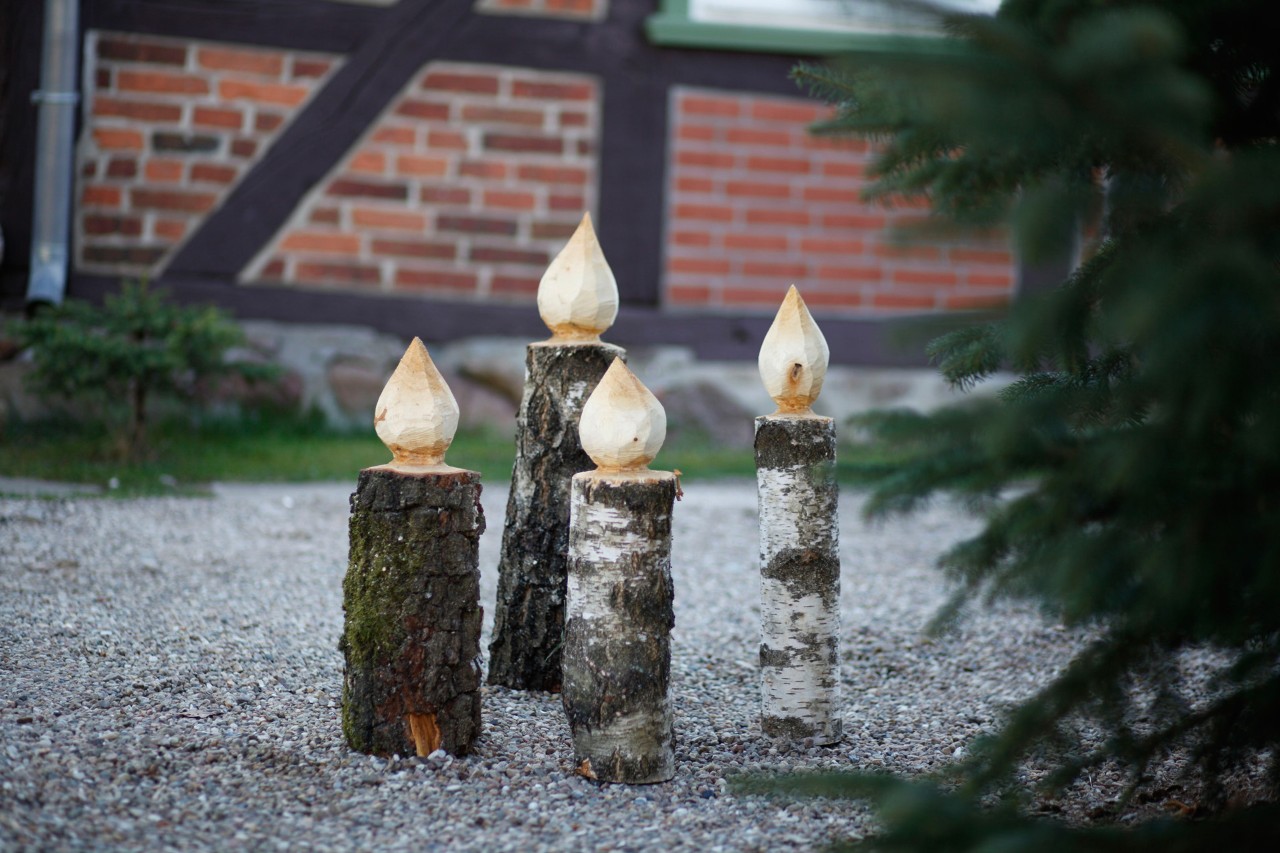 Cuatro velas de madera hechas a mano junto a un abeto
