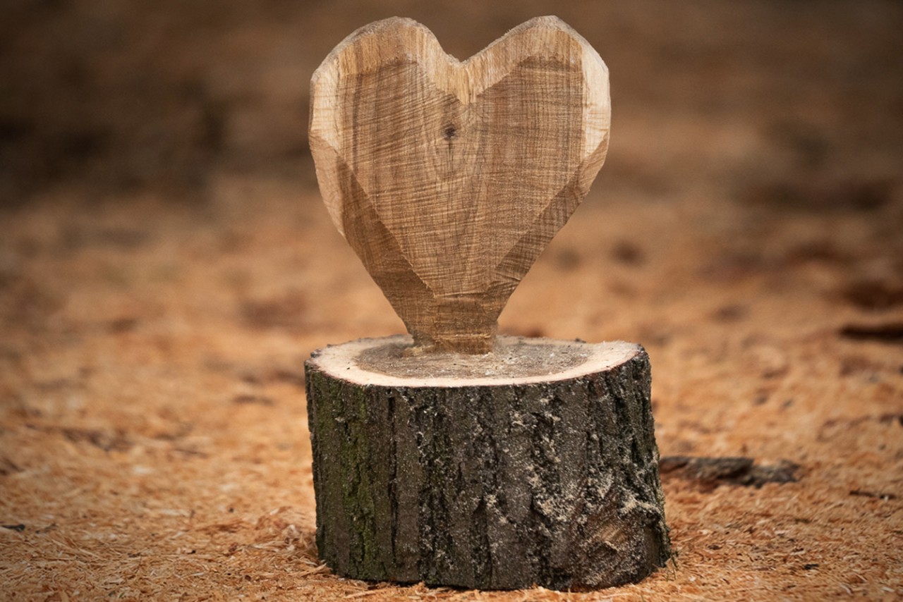 Un corazón de madera de bricolaje se encuentra en el suelo entre las virutas