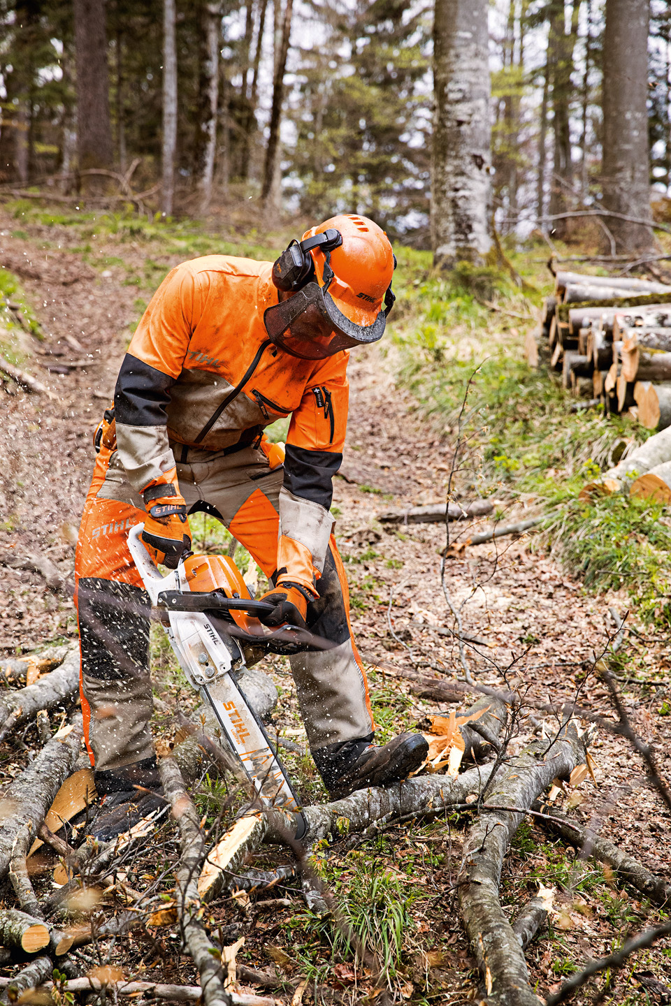 Un hombre combina equipos de protección auditiva durante el trabajo profesional en un bosque