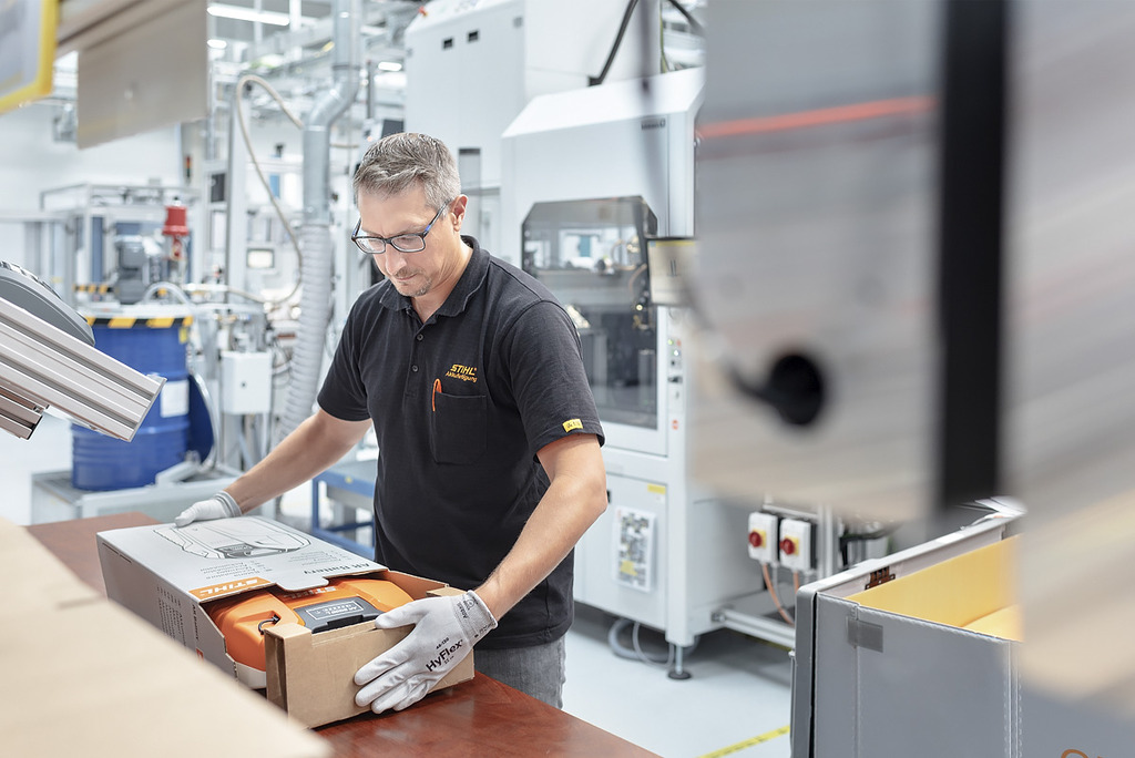 Un empleado de producción de baterías empaqueta una herramienta inalámbrica STIHL en una caja