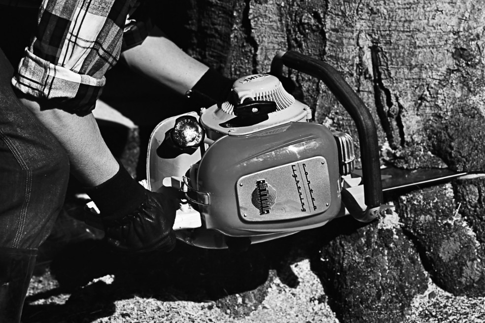 Antiguo primer plano en blanco y negro de alguien talando un árbol con la ayuda de una motosierra STIHL Contra