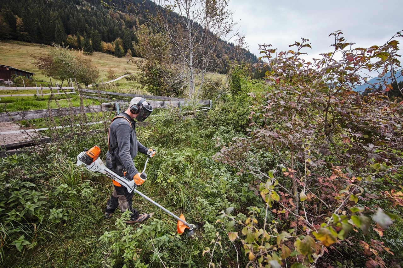 Un hombre con equipamiento de protección individual corta matorrales densos con una desbrozadora de gasolina STIHL FS 311