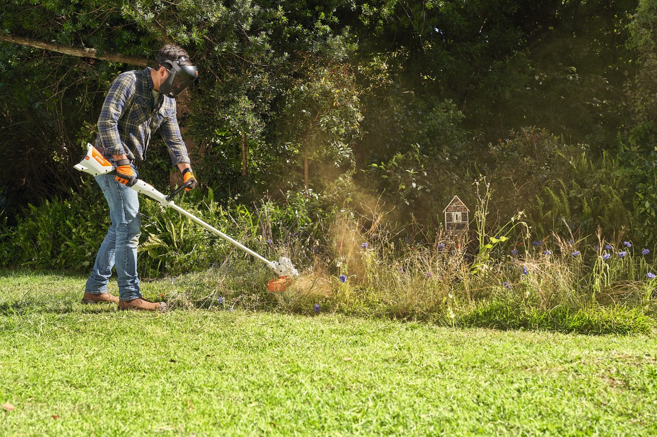 Un hombre siega un prado de flores silvestres con la STIHL FSA 57
